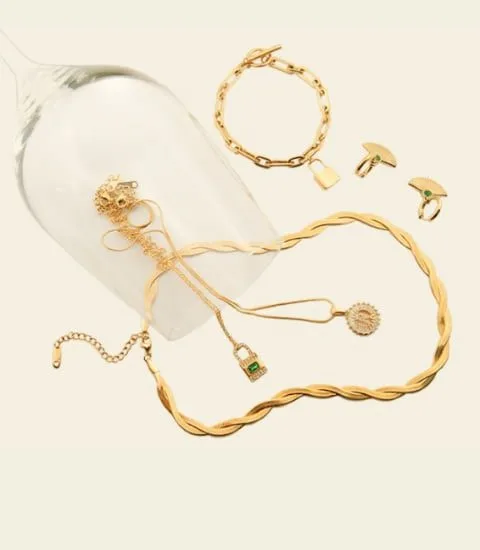 Bannière avec bijoux disposés à l'intérieur et autour d'un verre. Sur la photo, les bijoux suivants sont représentés : collier Opéra, boucles d'oreilles Spring, collier Dynasty et bracelet Lock.