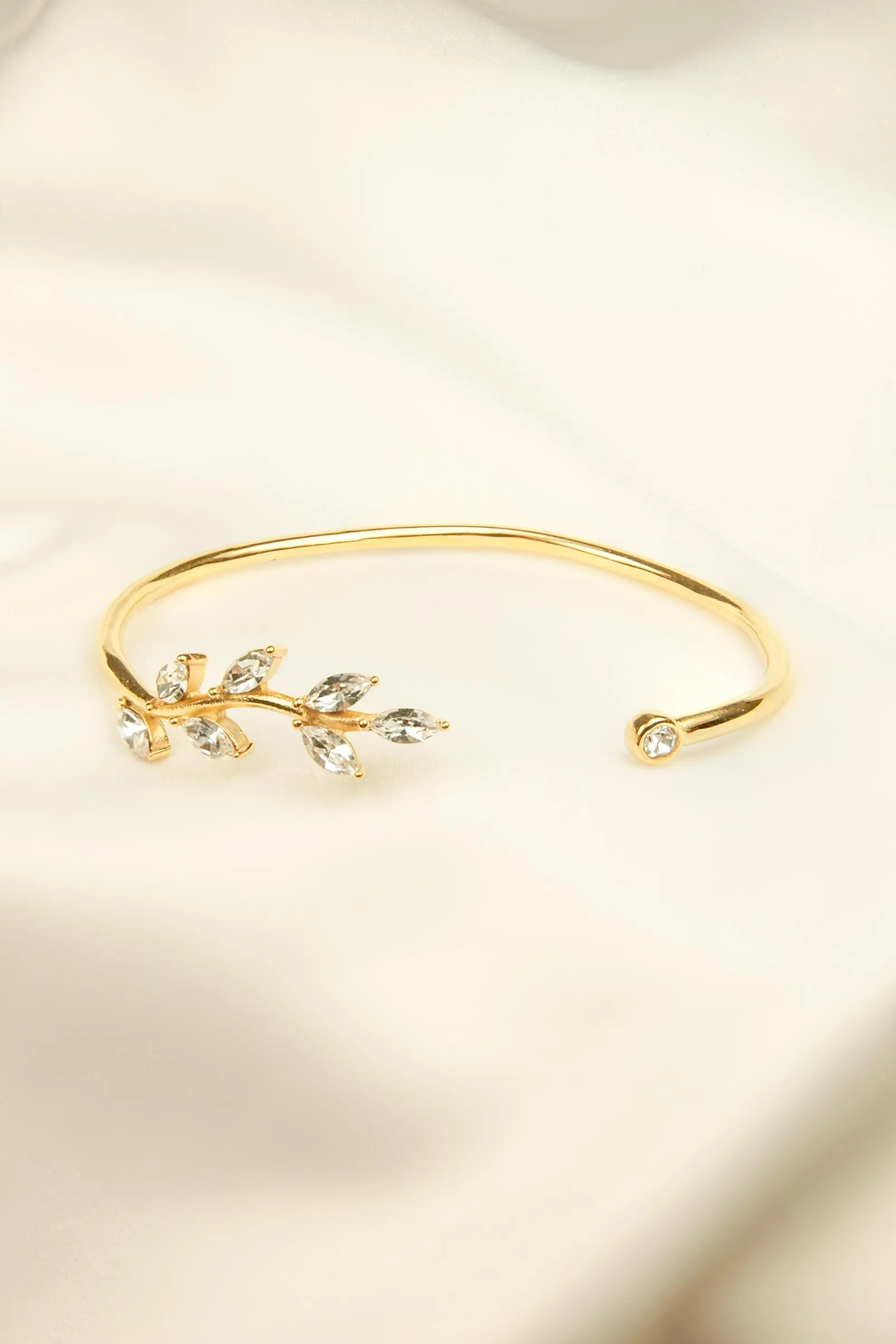Bracelet Glory blanc. Bracelet ajustable doré et en acier inoxydable, en forme de feuille de laurier et orné de zircons blancs.