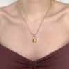 Collier Romance & Lock petit. Photo porté du pendentif doré et en acier inoxydable en forme de cadenas, de taille petite, avec sa chaîne maille serpent doré et en acier inoxydable.