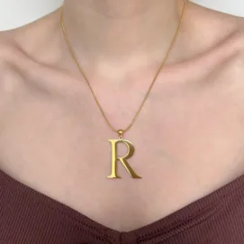 Collier Romance & Majestic. Photo porté du pendentif doré et en acier inoxydable en forme de lettre, ici R, de grande taille avec sa chaîne maille serpent doré et en acier inoxydable.